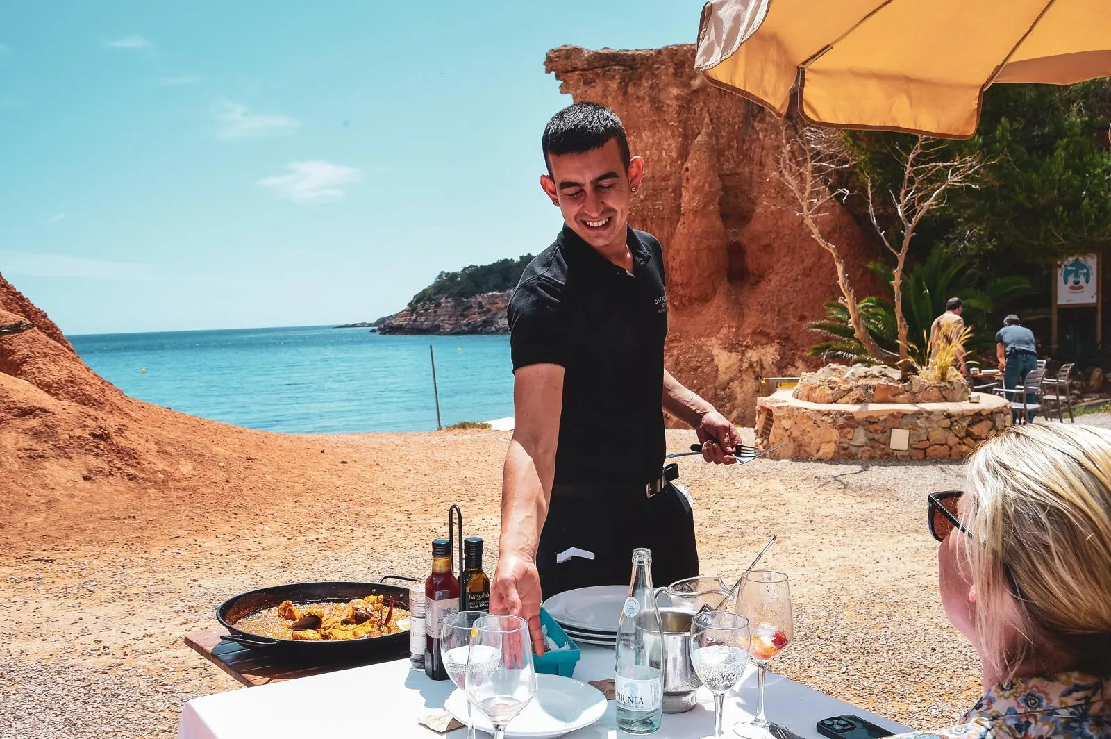 Kellner von Sa Caleta serviert Paella am Strand